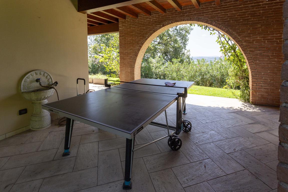 A table tennis table under the arched portico, looking out to the hills