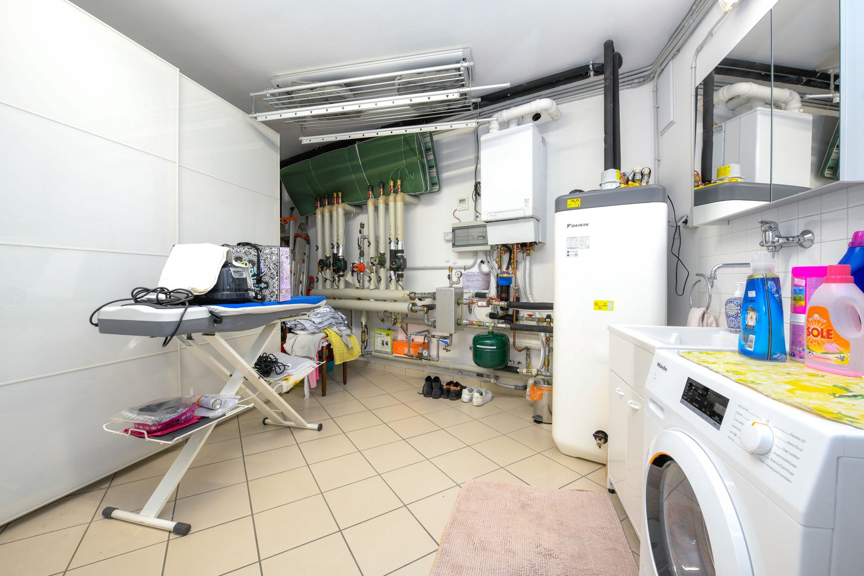 The laundry room at garage level, with washing machine, sink and drying racks